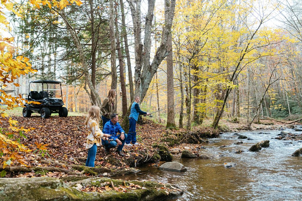 Family fishing and camping by the rive using their golf cart to get around